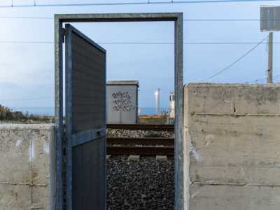 Sulla sinistra il muretto � interrotto da una porta in metallo che permette di attraversare i binari